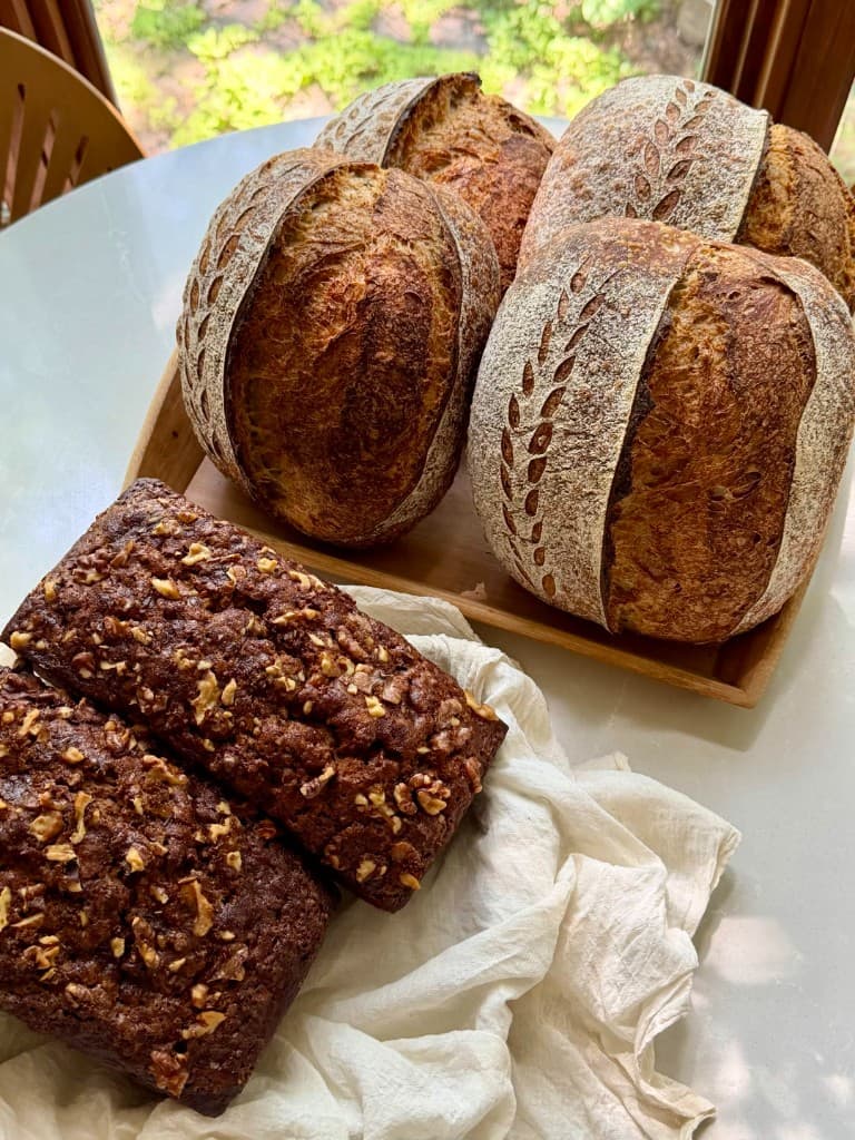 A selection of artisan sourdough loaves and banana walnut bread on a wooden board